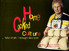 the cover of Home Cooked Culture is black, with a color photo of a grandmotherly woman with a pan of pastries to go in the oven.