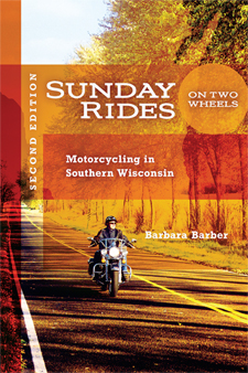 The cover of the second edition of Barber's popular motorcycling guide is orange in tone, with a photo of a man riding a Harley down a Wisconsin road.
