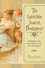 The Invisible Jewish Budapest: Cover showing a painting depicting three people, one wearing a dress and winking and the other two dressed as clowns. On the right side of the cover, the title text is proclaimed in a font that resembles caligraphy. The title text is located inside a long, manilla colored box.