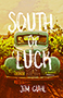 South of Luck: cover showing an old blue car in a field. The image is sepia tone with the title text written in white, all capps font, superimposed on top of it.