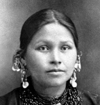 photo of Mountain Wolf Woman is an historical photo. Mountain Wolf Woman is young, has her hair parted in the middle and wears many earrings, or hair ornaments.